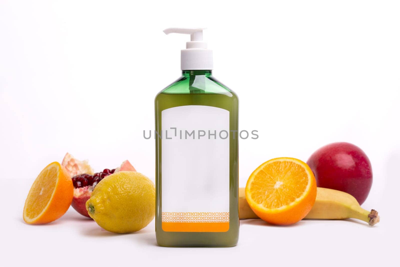 green bottle with dispenser without design next to fruit on a white background.