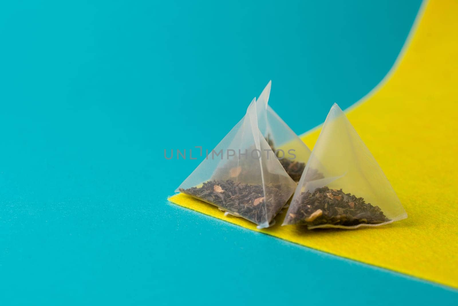 green tea in a pyramid bag on a yellow blue background.