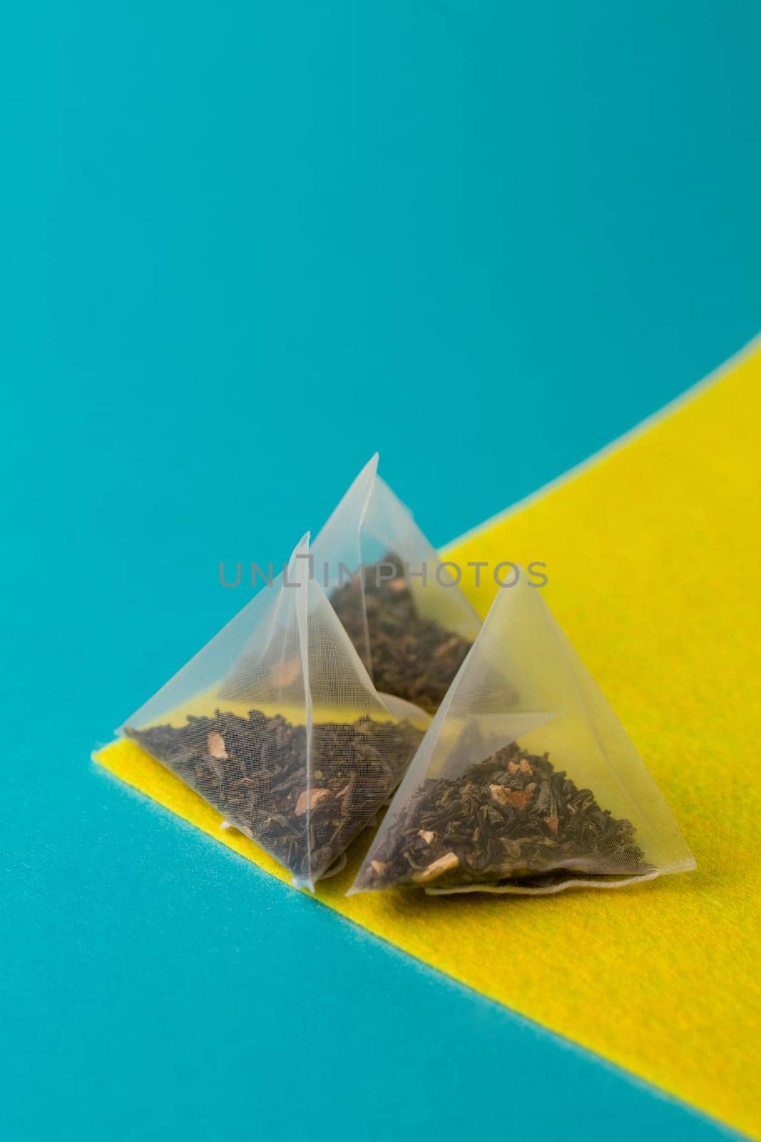 green tea in a pyramid bag on a yellow blue background.
