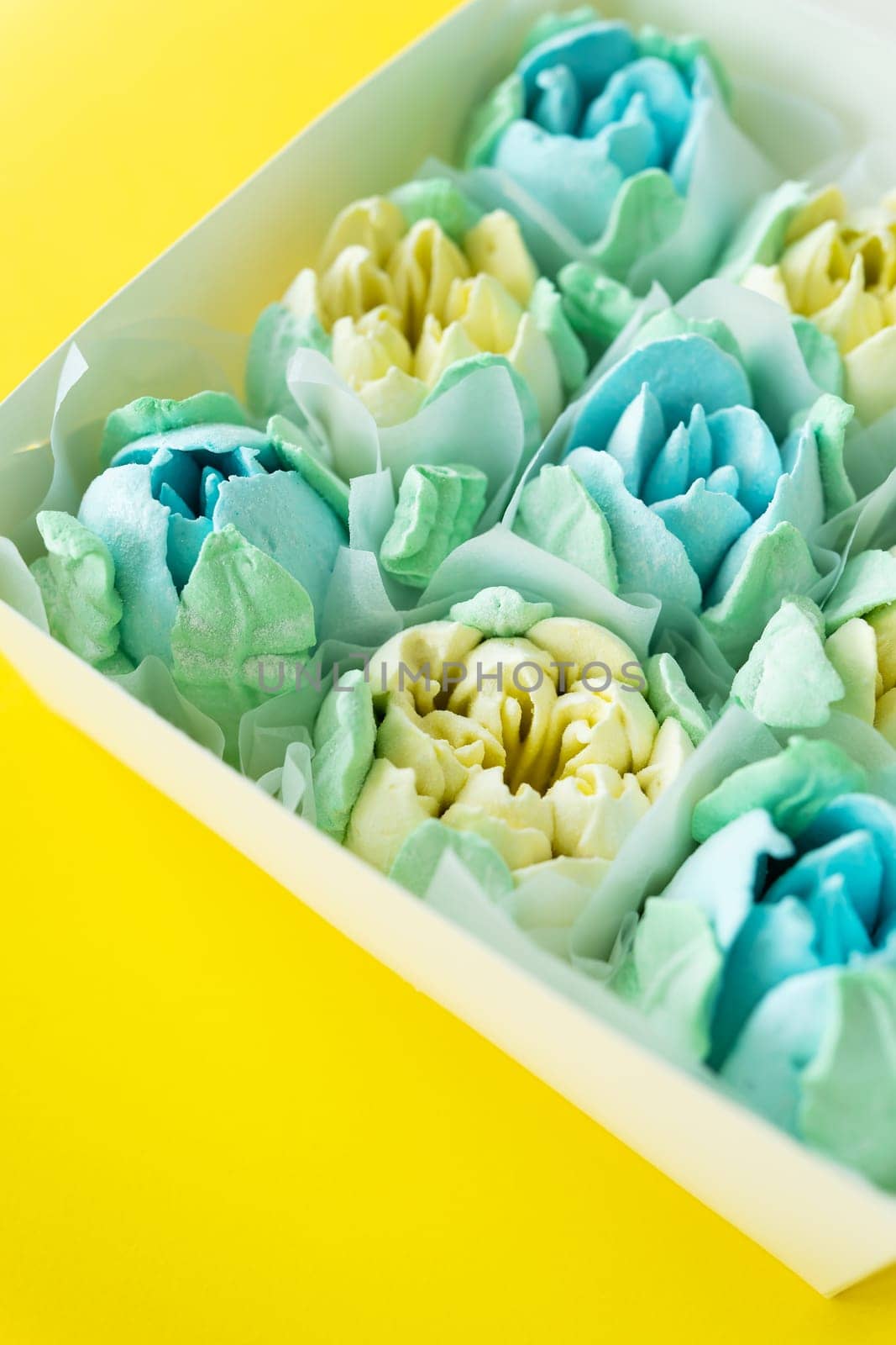 Box of colorful desserts in the shape of flowers on a two-color background. Marshmallow in the form of a rose