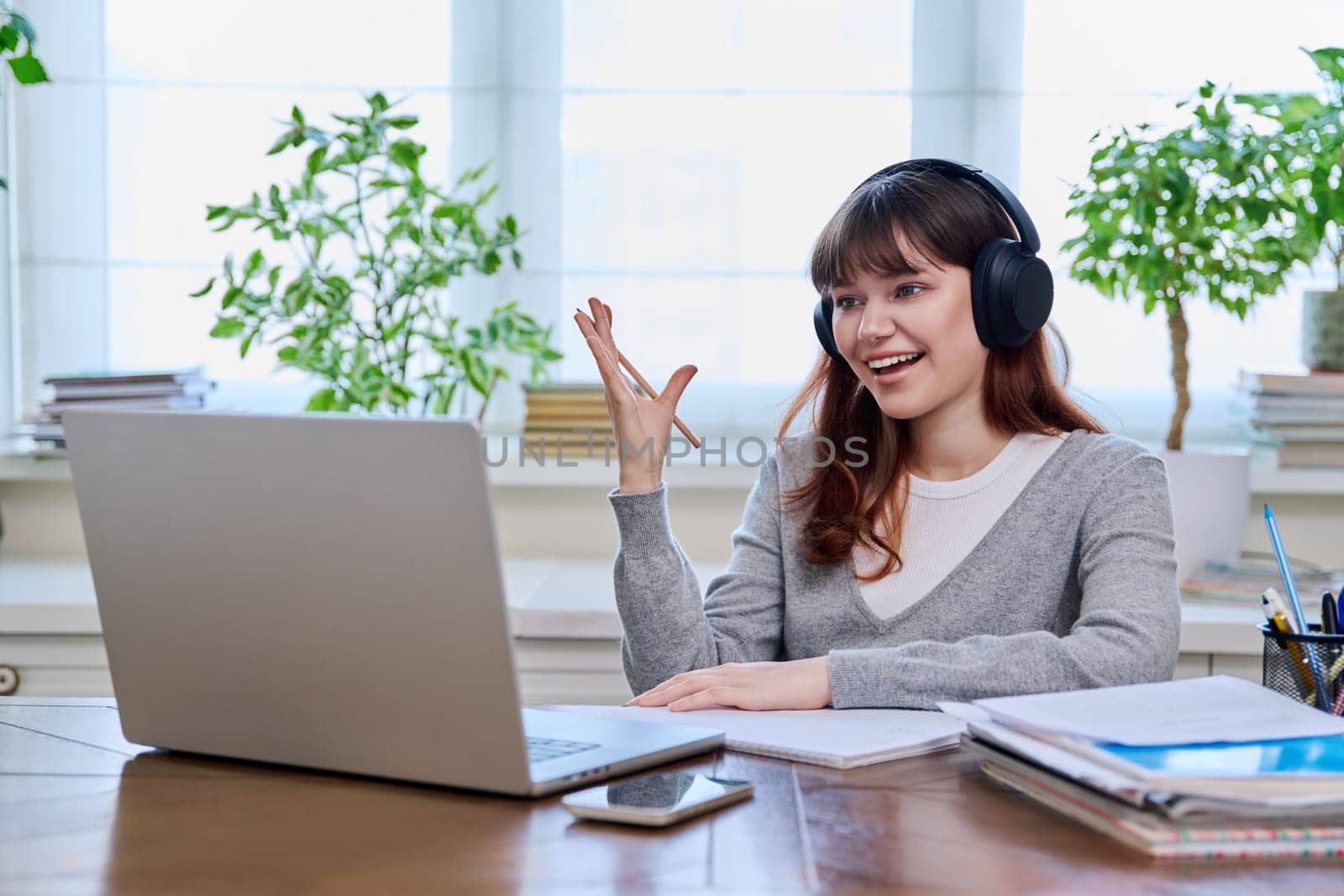 Girl teenage student in headphones having video chat online on computer by VH-studio