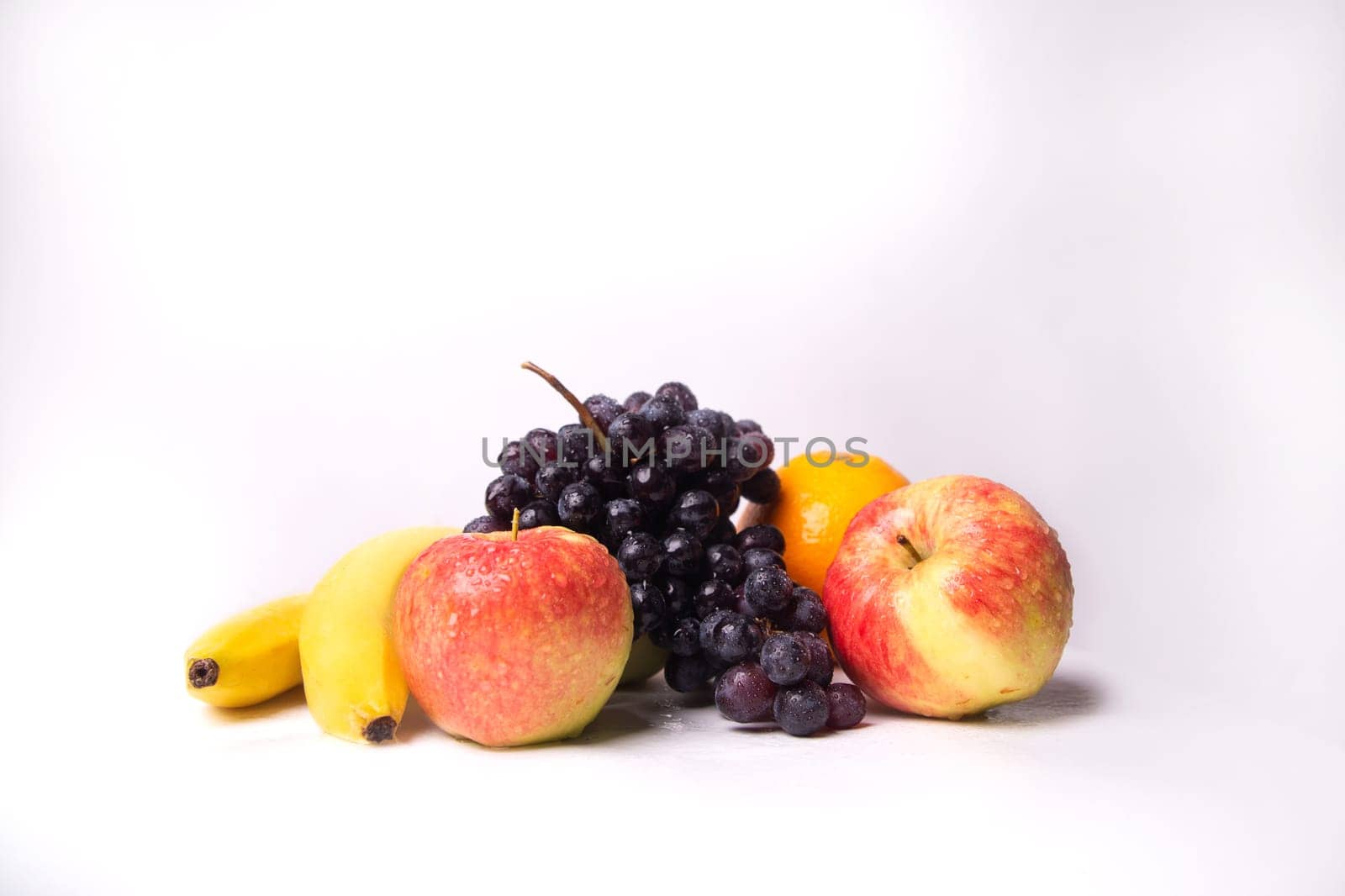 Still life of fruits on a white background, banana, apple, grapes.