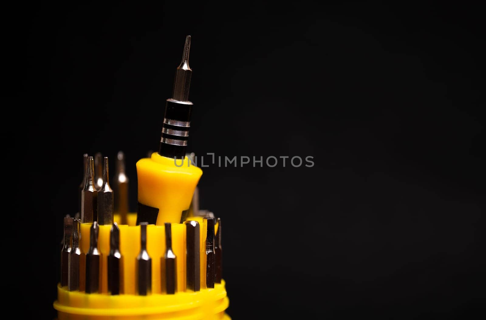 a set of yellow screwdrivers on a black background.