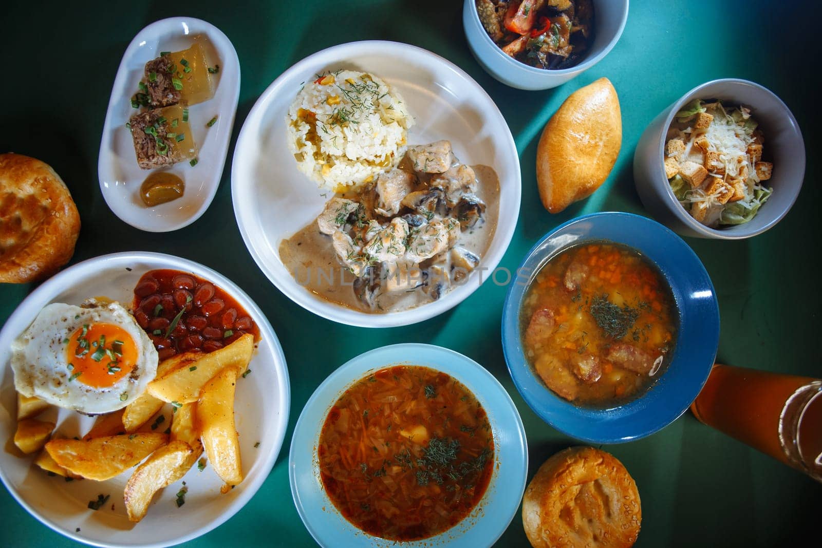 A variety of delicious and healthy food displayed on a green table. The spread features soups, salads, bread, and refreshing drinks.