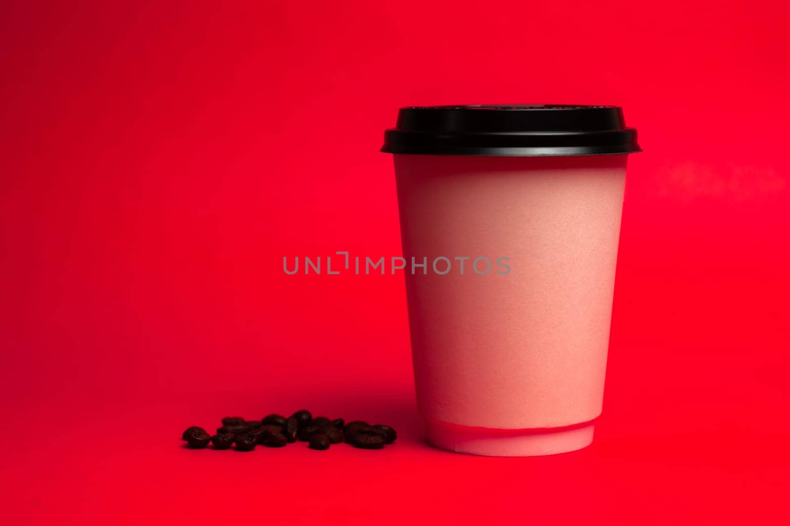 white paper cup with coffee beans on a red background.