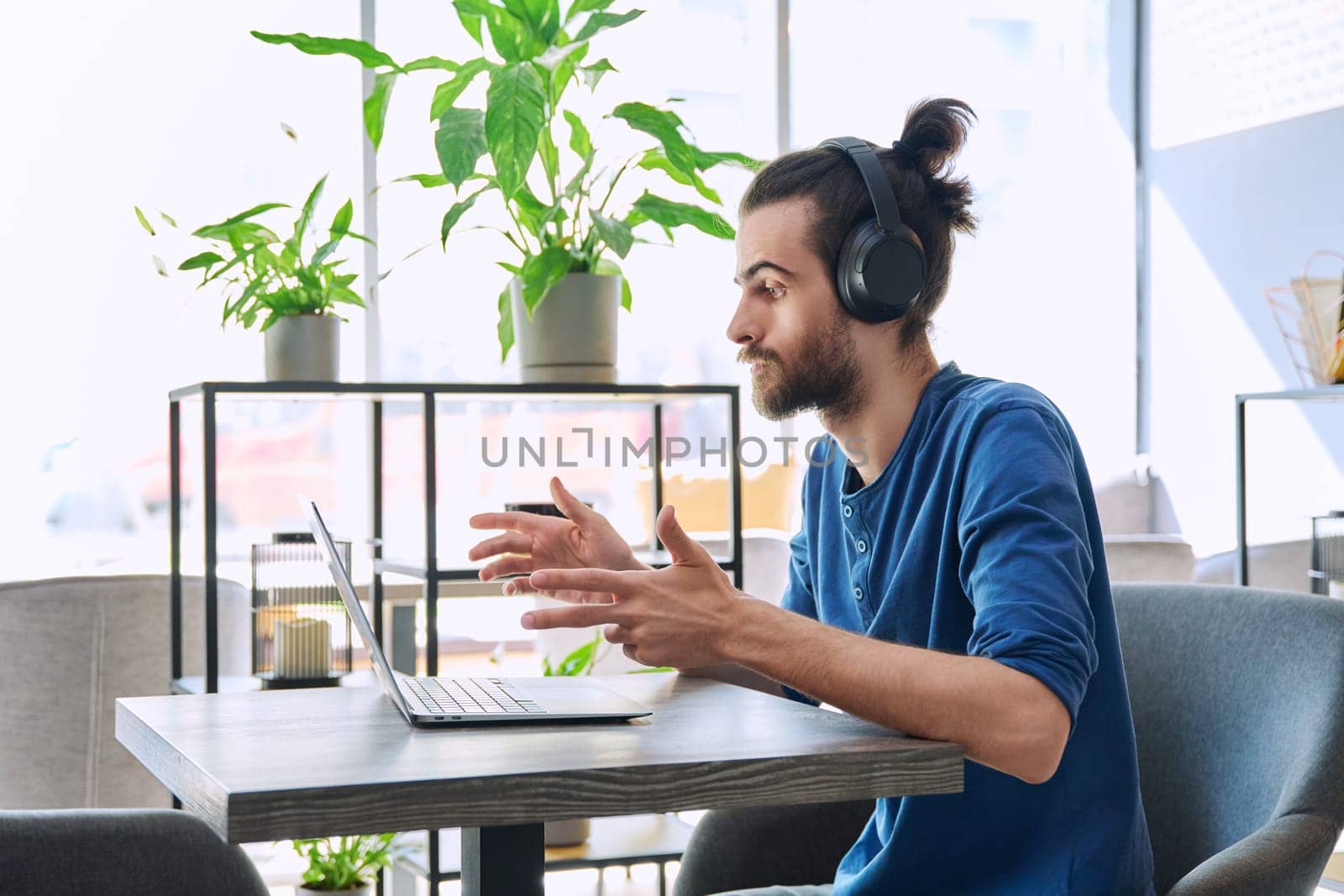 Young handsome man in headphones having work video chat using laptop by VH-studio