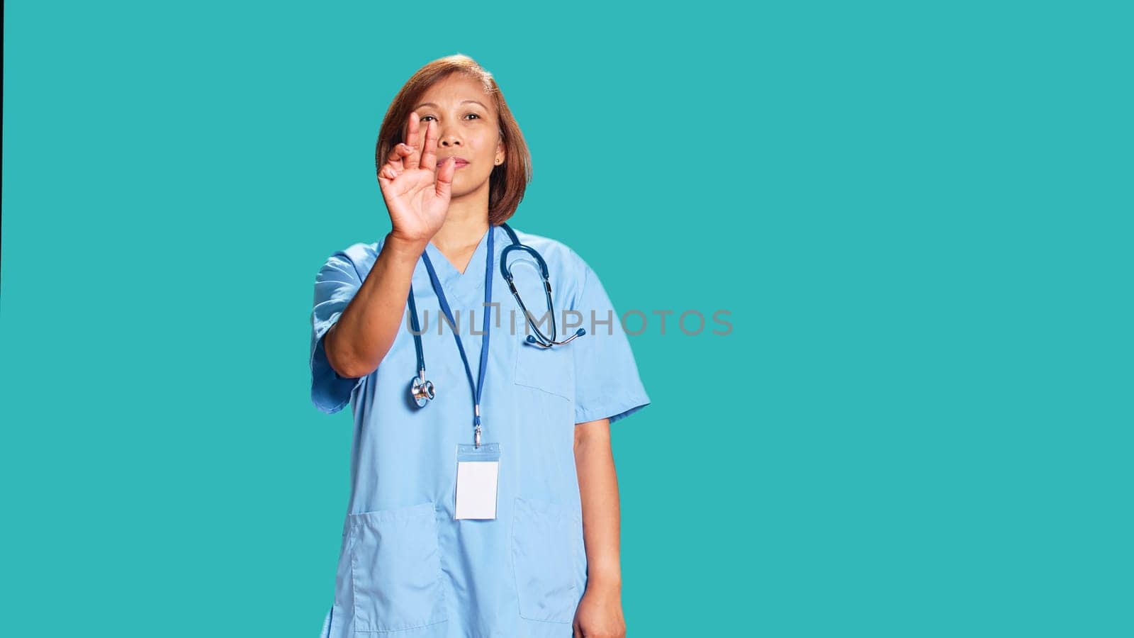 Nurse doing swiping hand motions, remotely controlling tactile screen. Healthcare specialist working in high-tech futuristic modern medical clinic, isolated over blue studio background