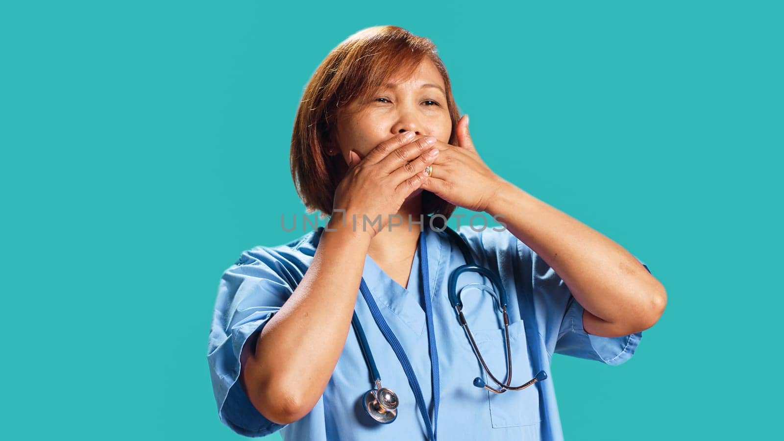 Nurse covering mouth with hands by DCStudio