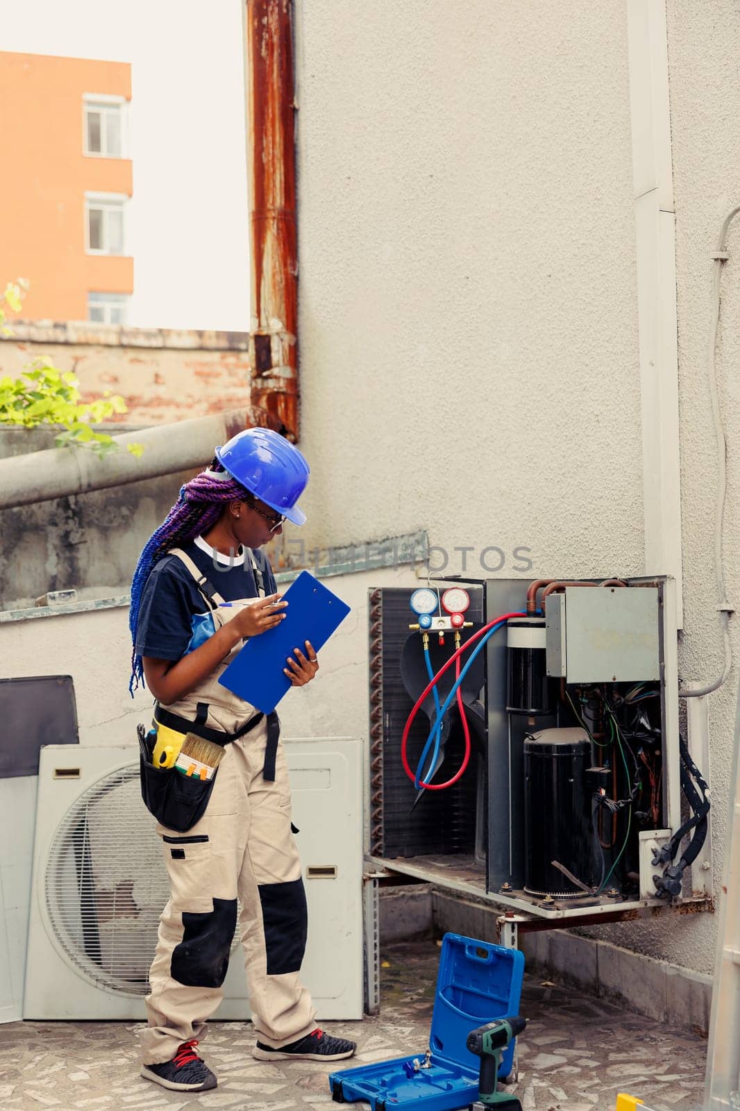 Efficient technician commissioned to optimize HVAC system performance, ensuring it operates at maximum efficiency. Seasoned mechanic doing air conditioner checkup, imputing data on clipboard