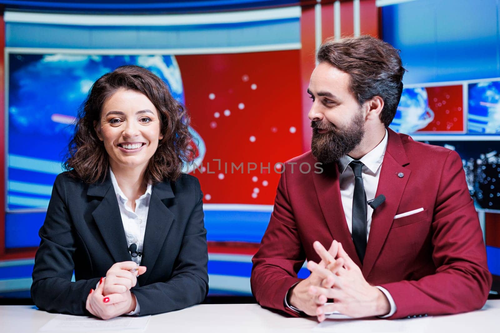 Show hosts going live on broadcast to read breaking news stories and international events, delivering television content from media newsroom. Team of journalists presenting headlines.