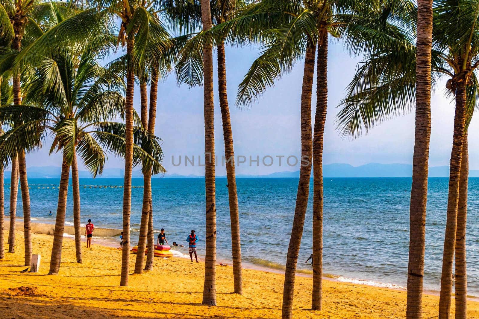 Pattaya Chon Buri Thailand 25. October 2018 Tropical beach waves water sand people boat palm trees and skyscrapers in Jomtien Beach Pattaya Bang Lamung Chon Buri Thailand in Southeastasia Asia.