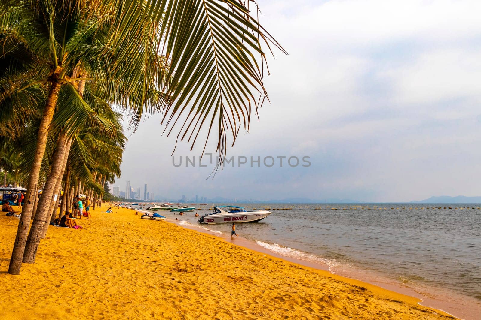 Pattaya Chon Buri Thailand 25. October 2018 Tropical beach waves water sand people boat palm trees and skyscrapers in Jomtien Beach Pattaya Bang Lamung Chon Buri Thailand in Southeastasia Asia.