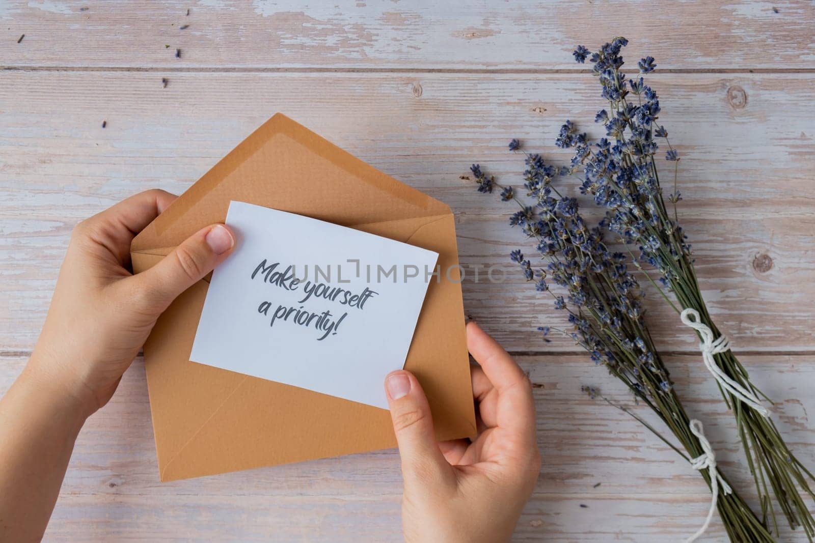 MAKE YOURSELF A PRIORITY text on supportive message paper note reminder from beige envelope. Flat lay composition dry lavender flowers. Concept of inner happiness, slowing-down digital detox personal fulfillment. Top view