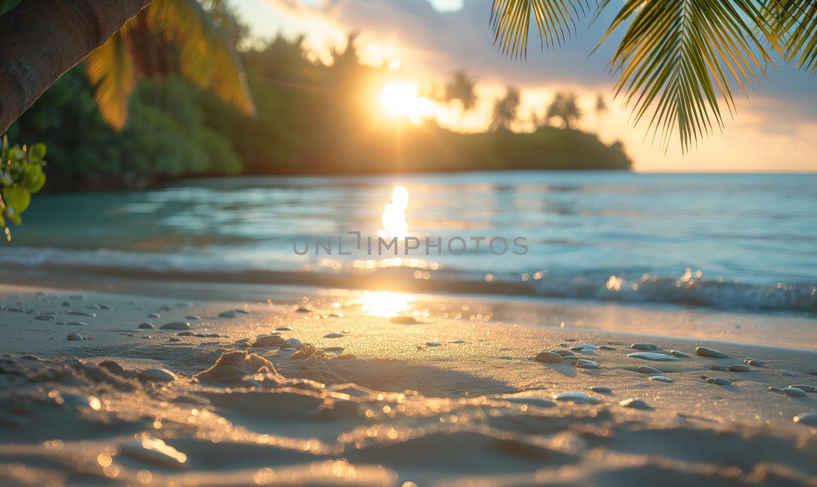 The sun dips below the horizon of a tropical beach, casting warm colors across the sky and water.