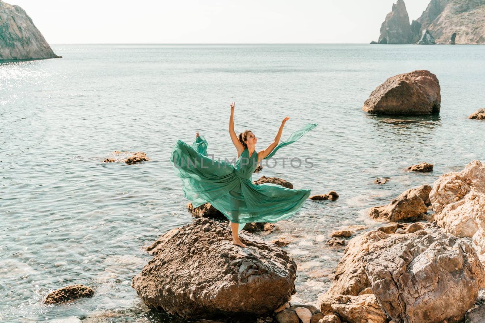 Woman green dress sea. Female dancer in a long mint dress posing on a beach with rocks on sunny day. Girl on the nature on blue sky background. by Matiunina