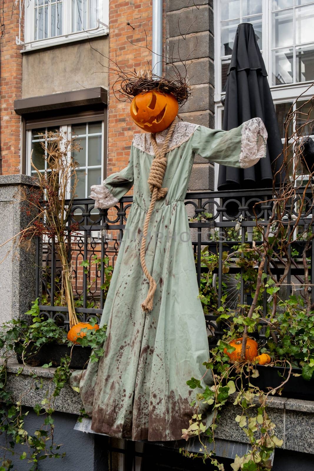 Exterior Beautiful atmospheric halloween scary scarecrow pumpkin decorated on porch. Autumn leaves and fall flowers celebration holiday Thanksgiving October season outdoors by anna_stasiia