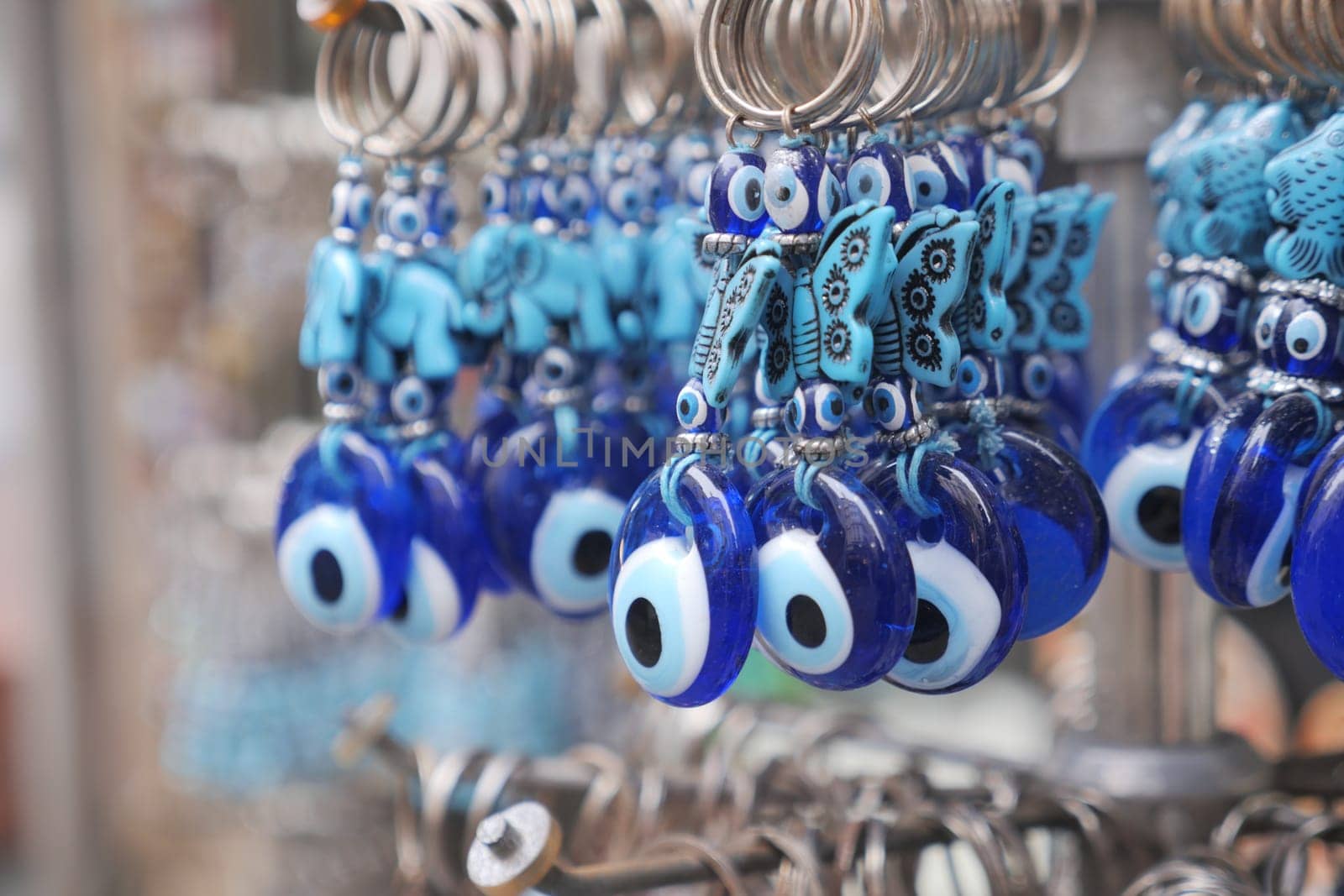 a bunch of blue evil eye keychains hanging on a shelf,