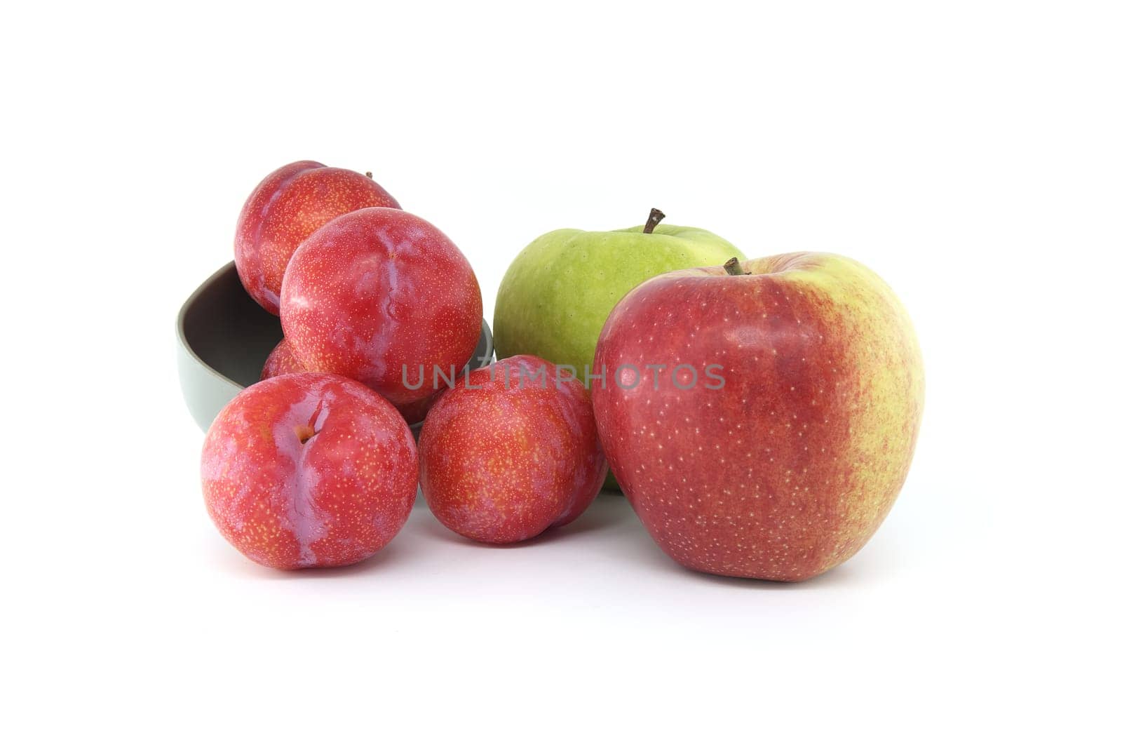 Red plums and green apple isolated on white background by NetPix