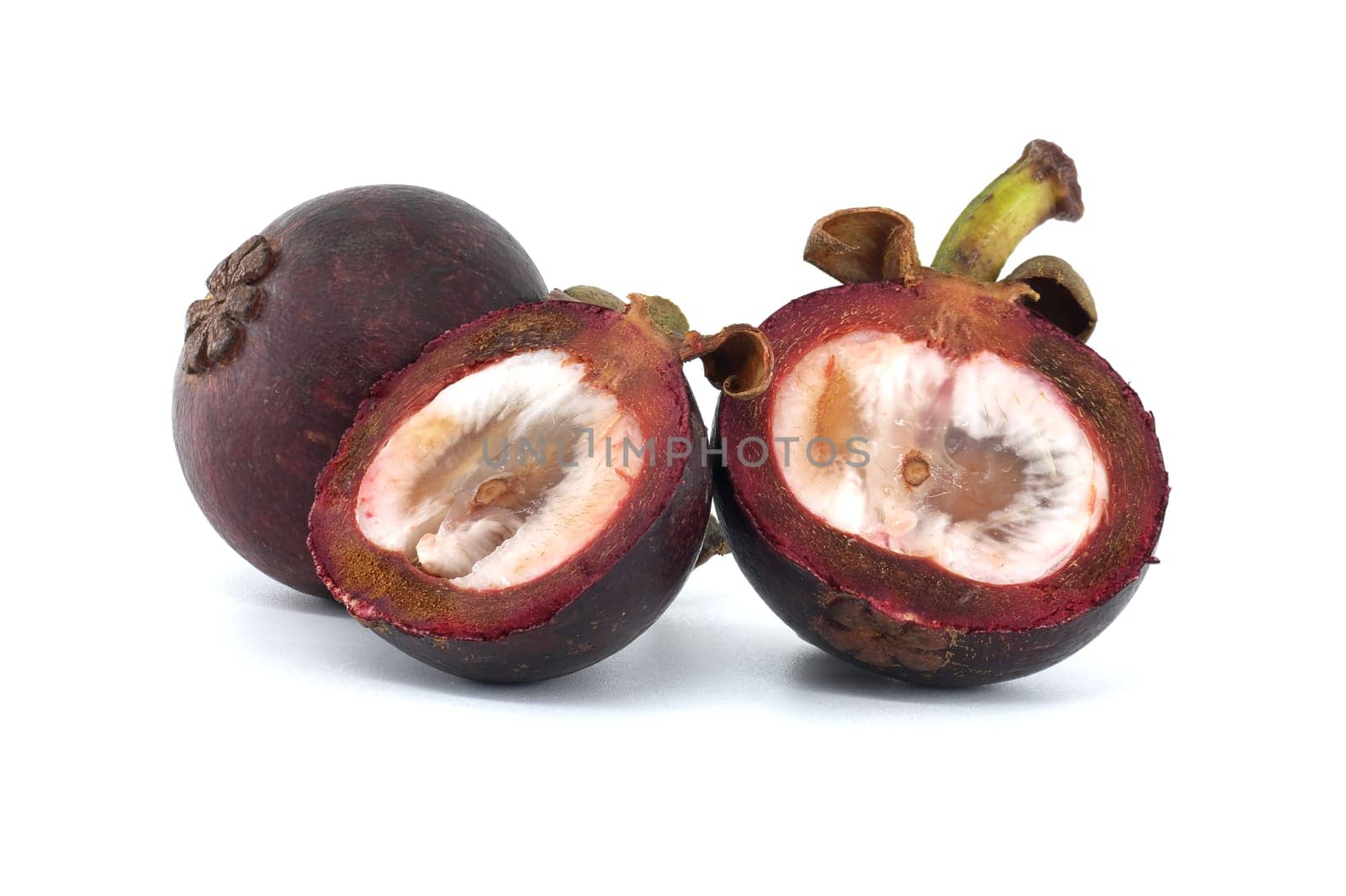 Whole and halved mangosteen fruits display their white inner flesh, speckled with dark purple spots and featuring two discernible black seeds, set against a white background