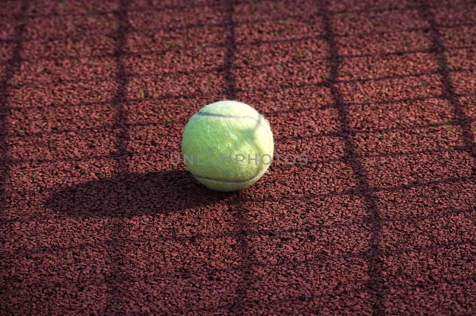 Yellow tennis ball is resting on tennis hard court surface by NetPix