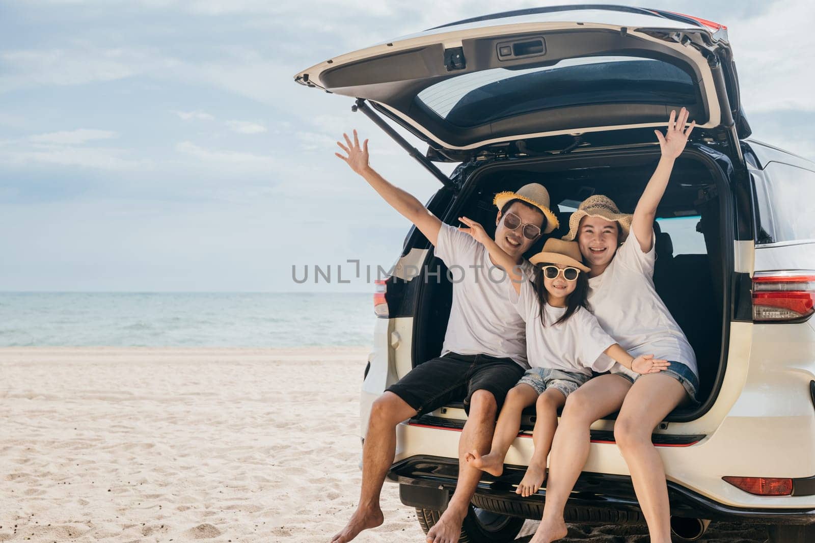 Family Day. Father, Mother and daughter enjoying road trip sitting on family back car raise hand up, Happy people having fun in summer vacation on beach, Family traveling in holiday at sea beach