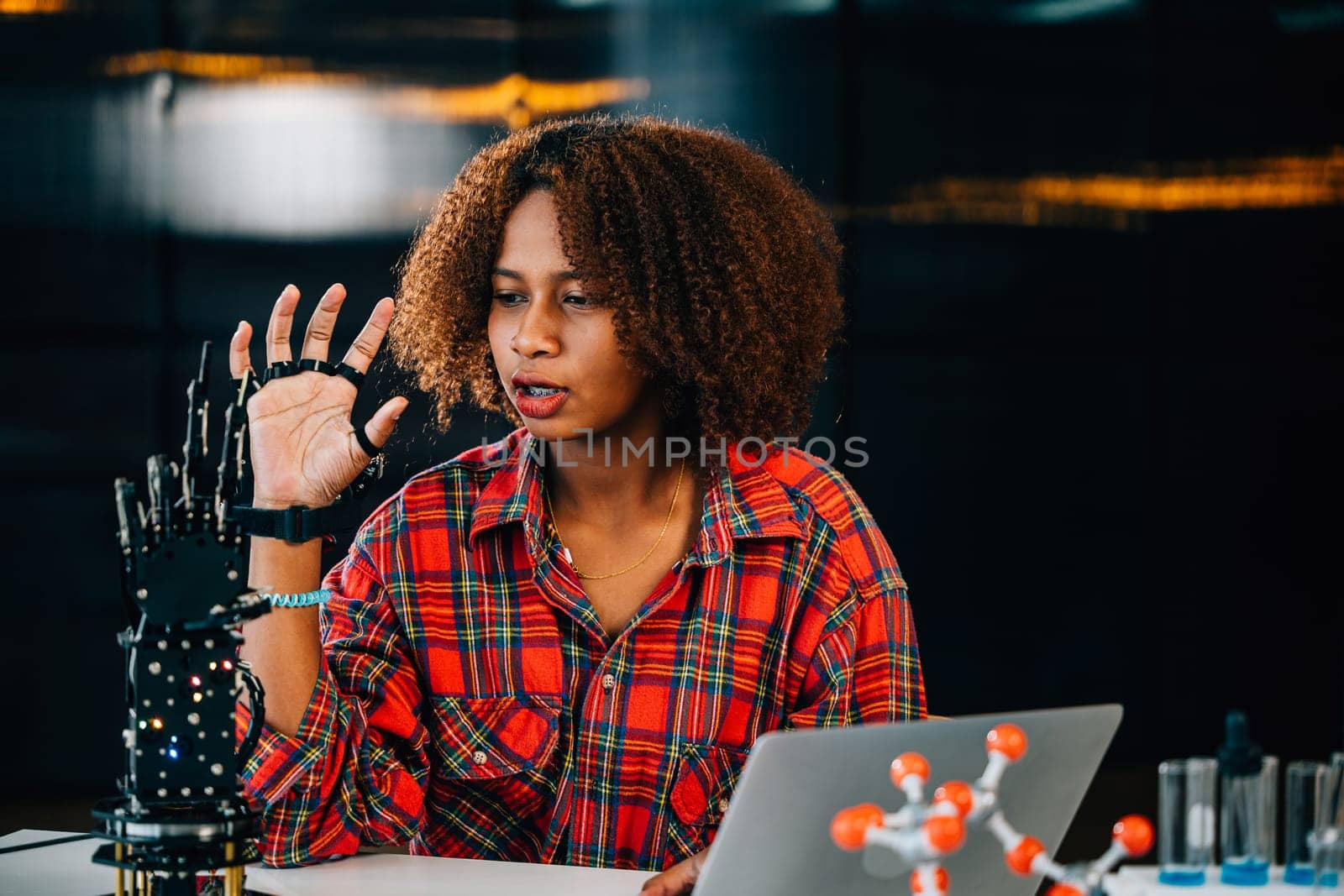 Portrait of a Black teenage student in a classroom learning about a robotic arm for her engineering project. She skillfully controls the arm showcasing intelligence and innovation in technology. by Sorapop