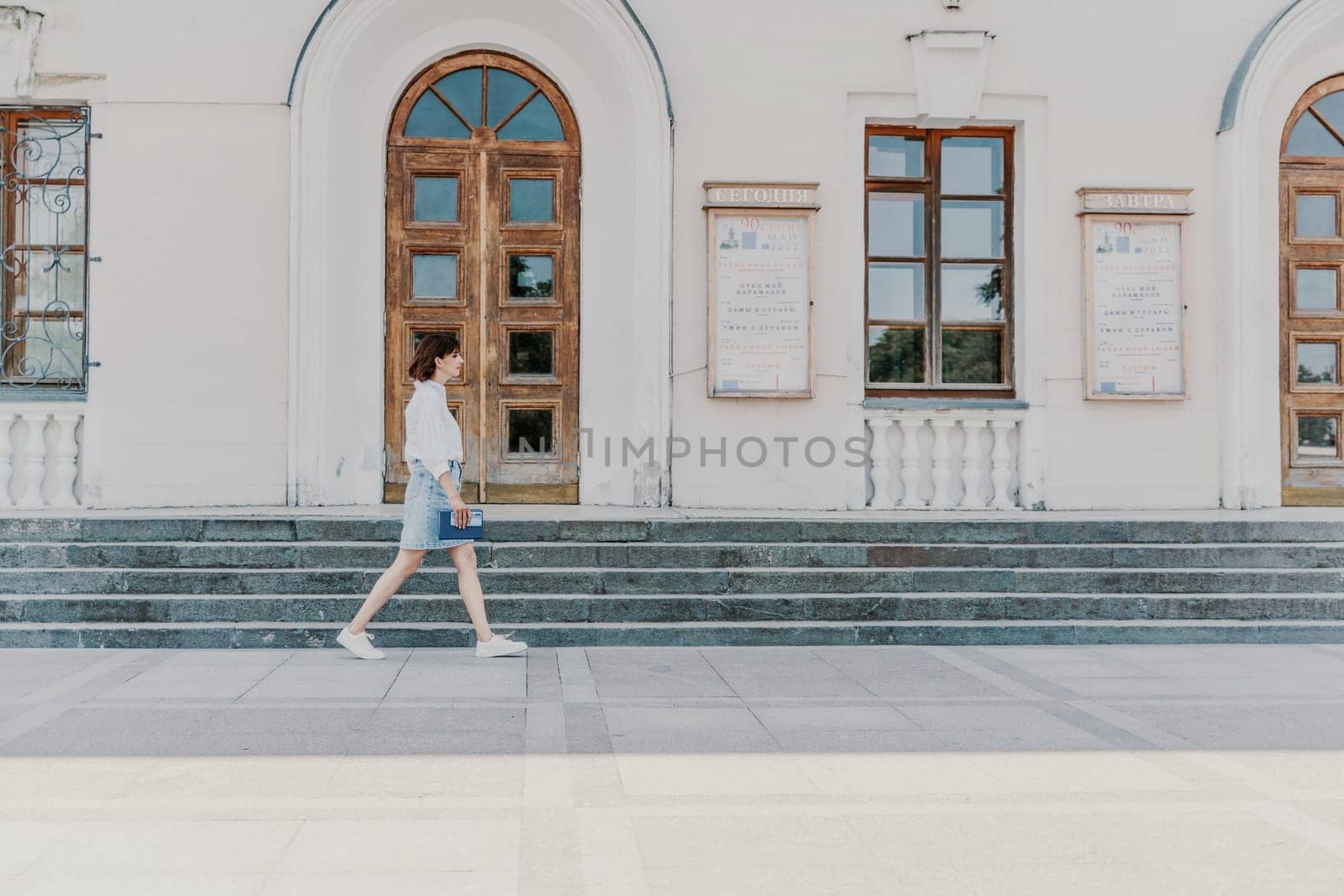 Woman staircase city. A business woman in a white shirt and denim skirt walks down the steps of an ancient building in the city.