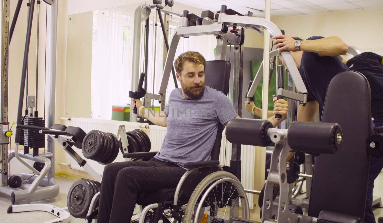 Disabled man in wheelchair doing hand exercises by Chudakov