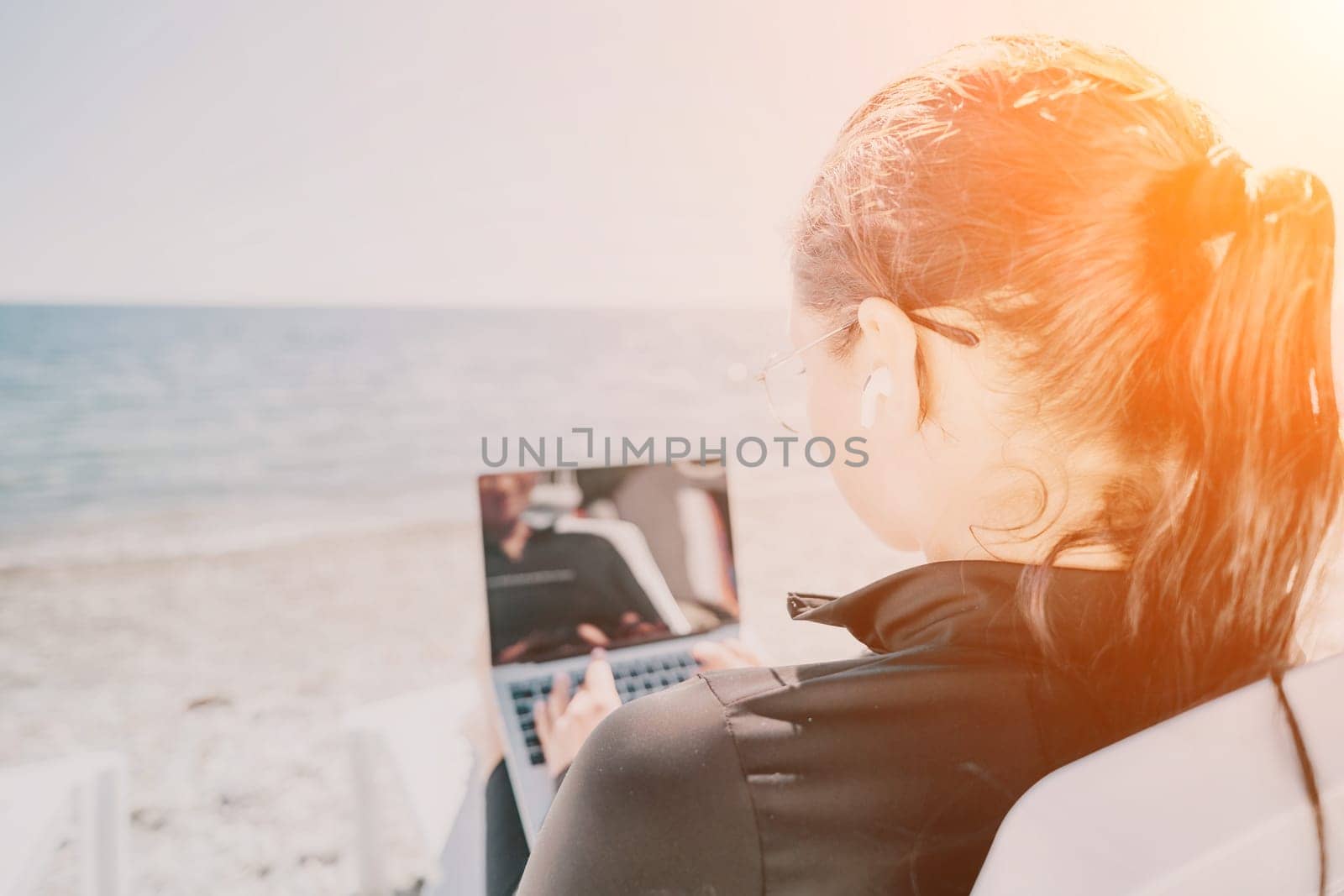 woman laptop sea. Working remotely on seashore. Happy successful lady, freelancer working on sea beach, relieves stress from work to restore life balance. Freelance, remote work on vacation by panophotograph