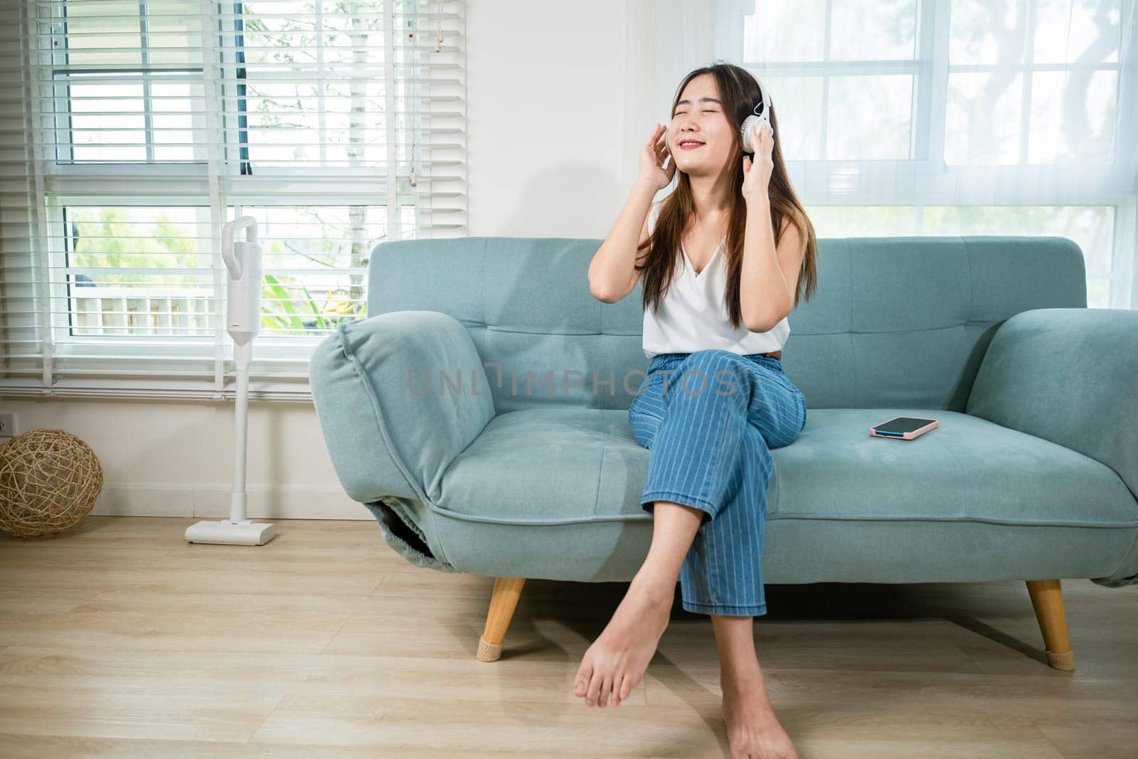 woman wearing headphones listening to music with smart mobile phone and relaxing by Sorapop