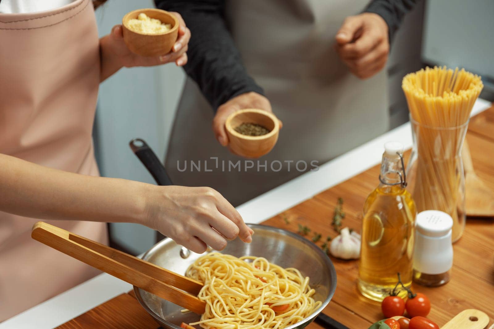 Close up of hand couple chef influencers cooking spaghetti mix ingredient taking to frying pan, putting seasoning and tasty sauce to make good flavor, Concept of presenting homemade food. Postulate.