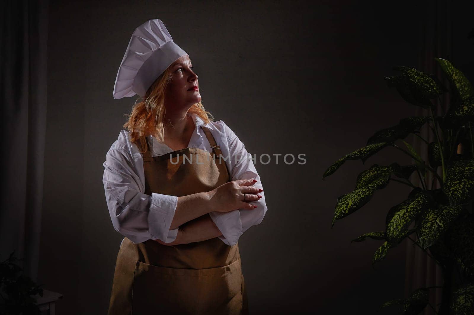A fat funny female cook in a hat and apron poses in the kitchen and takes selfie. Good cooking and body positive