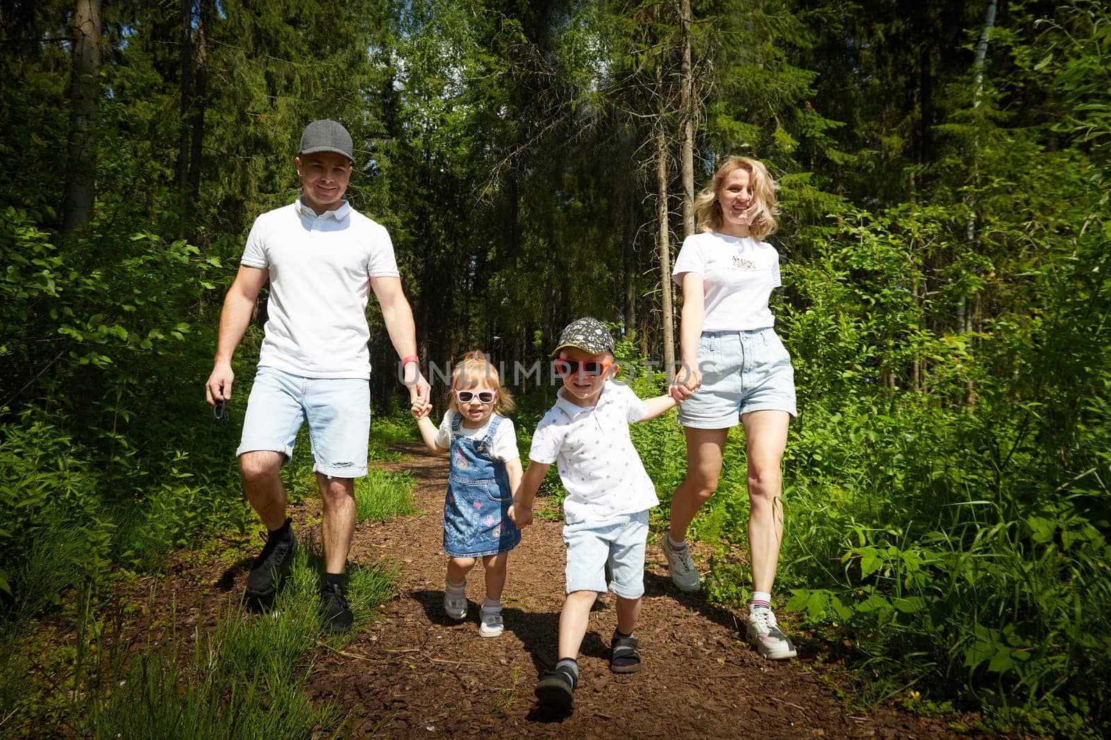 A man, woman, and child having fun and playing in the forest or park in summer or spring sunny day by keleny