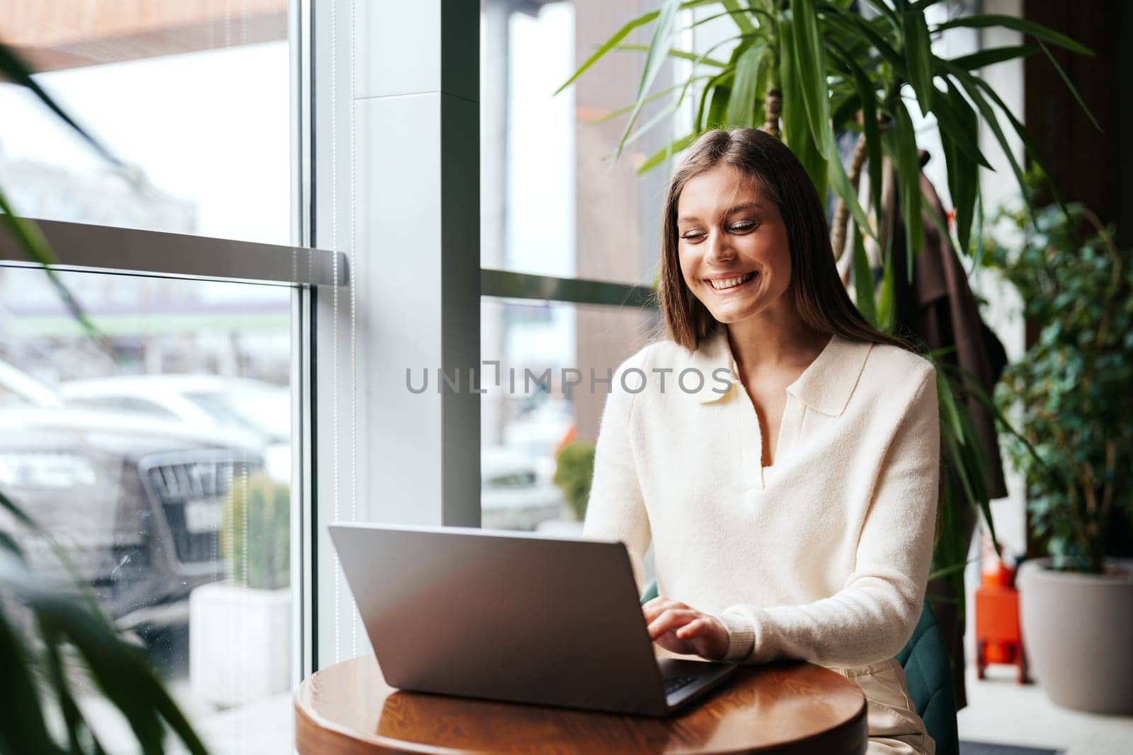 Smiling Woman Working on Laptop at a Cafe During Daytime by Fabrikasimf