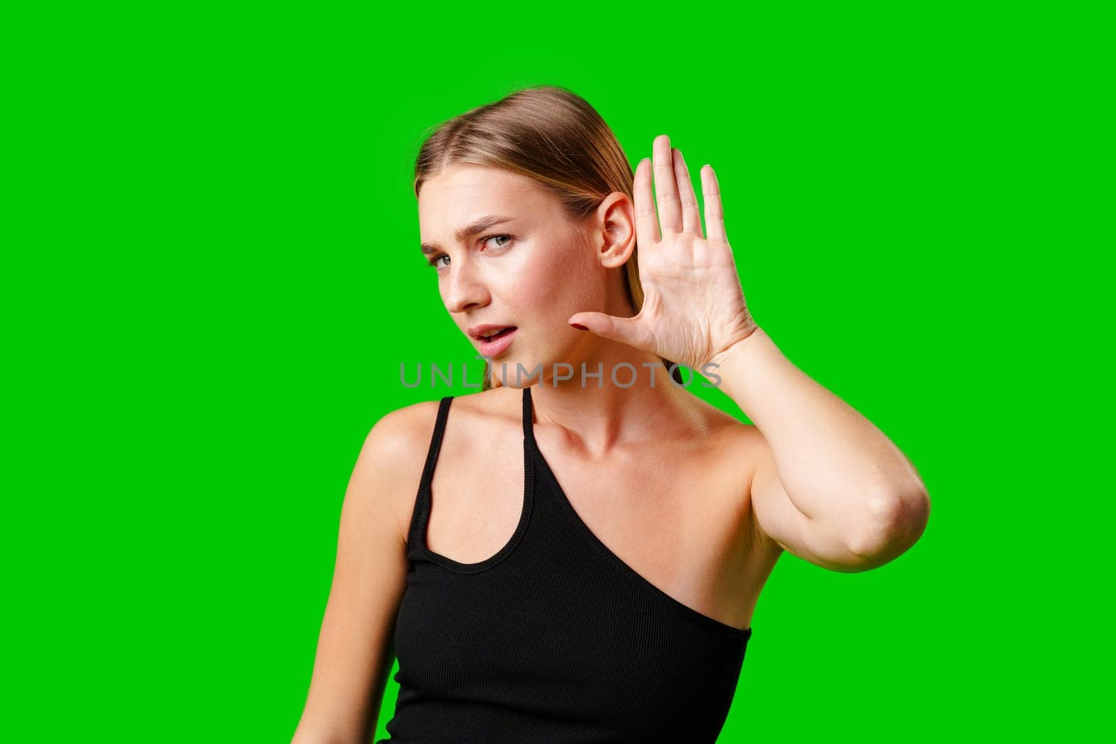 Young Woman in Black Top Holding Hand to Ear against green background