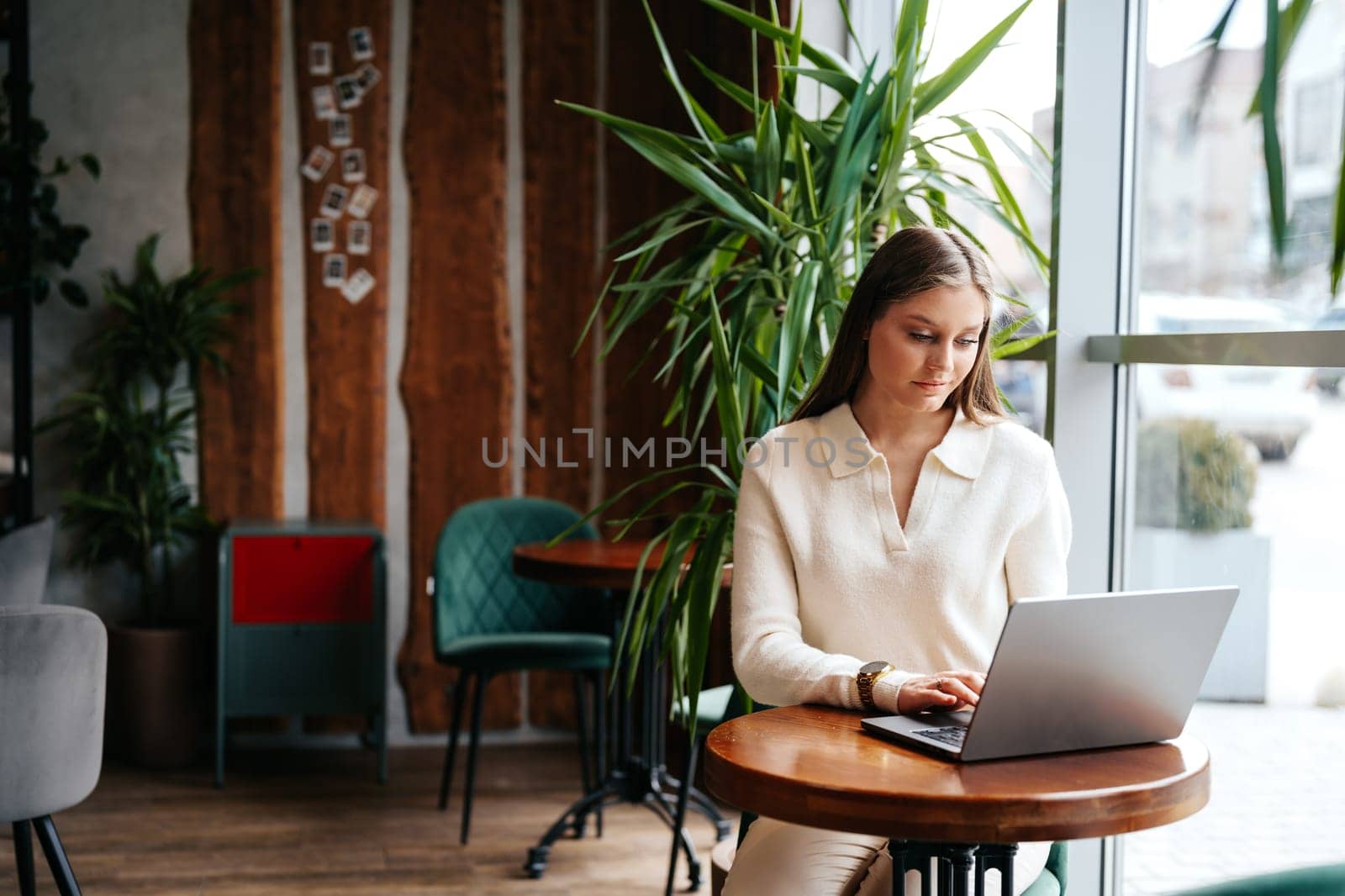 Woman Sitting at Table Using Laptop Computer by Fabrikasimf
