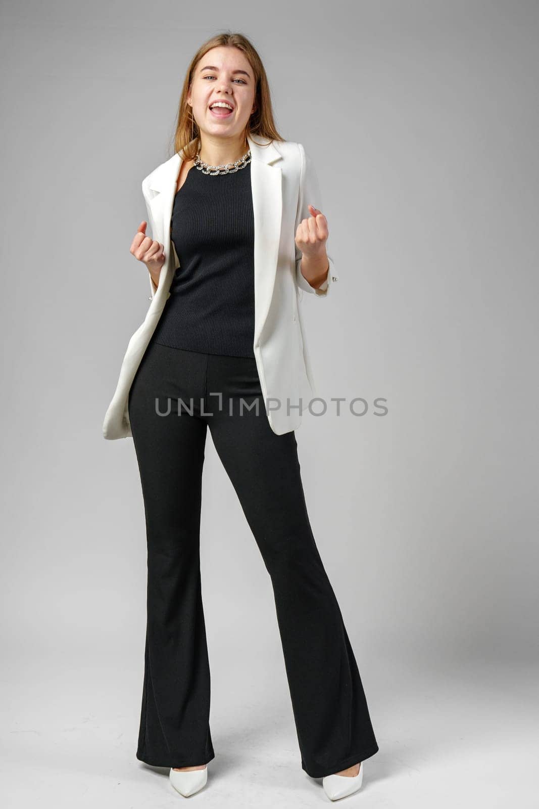 Confident Young Businesswoman Flexing Muscles in Smart Casual Attire Against Grey Background close up