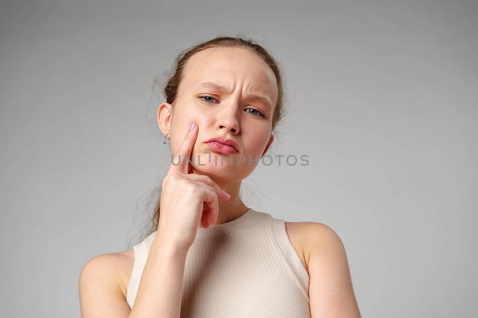 Young Woman Posing deep in thought on gray background close up