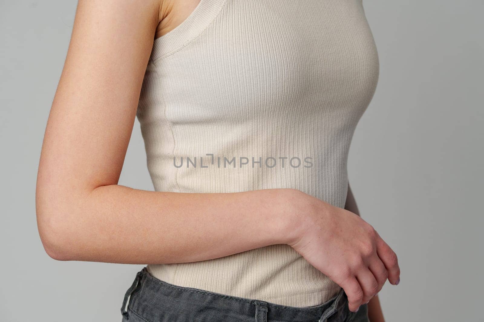 Female body in beige top on gray background by Fabrikasimf