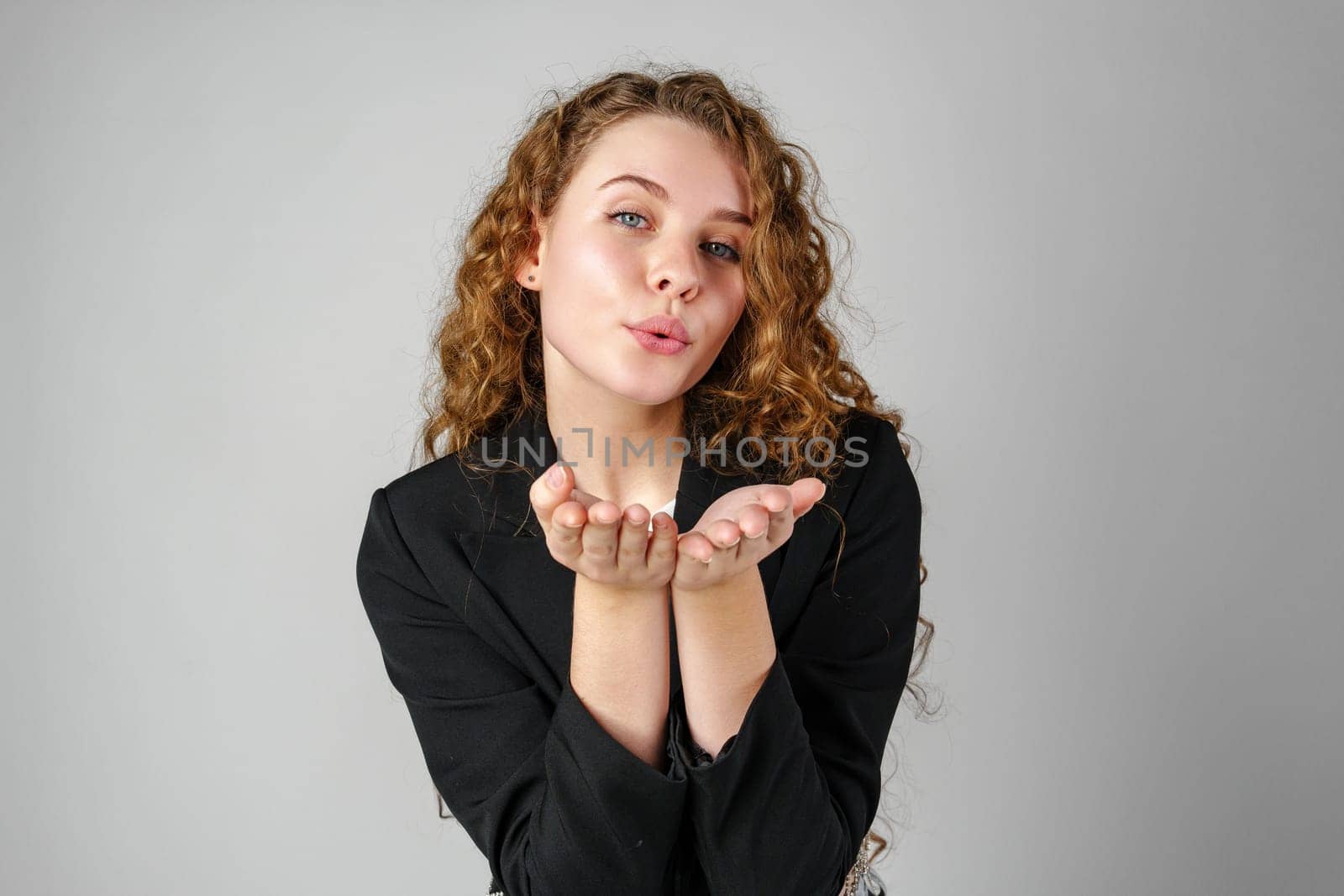 Young Woman Blowing a Kiss Towards the Camera in a Studio Setting by Fabrikasimf
