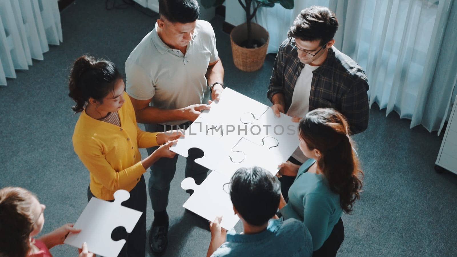 Top view of smart business people put last piece of jigsaw puzzle together to complete puzzle and standing while wearing casual cloth. Group of diverse team finding solution with teamwork. Symposium.