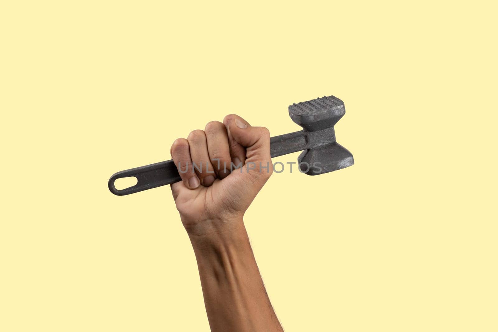 Black male hand holding a kitchen hammer isolated on yellow background by TropicalNinjaStudio