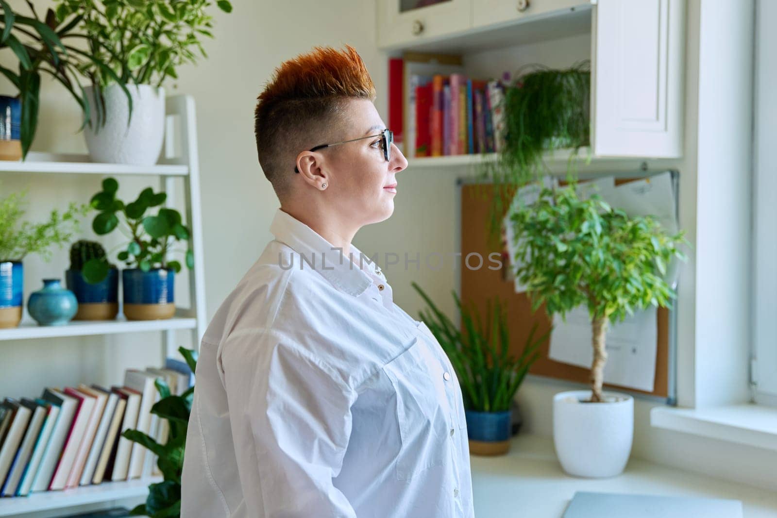 Profile portrait of serious middle-aged woman in glasses with red haircut by VH-studio