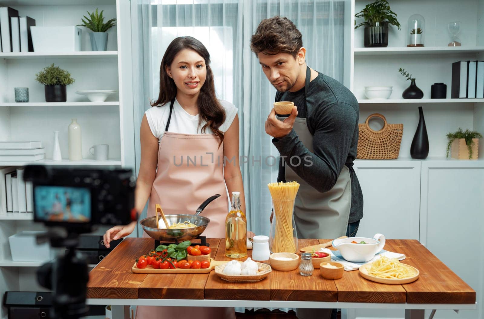 Couple chef influencers on cooking show presenting ingredient of spaghetti, meat, chilli, tomato, garlic and seasoning sauce's homemade special recipe recording on camera on live channel. Postulate.