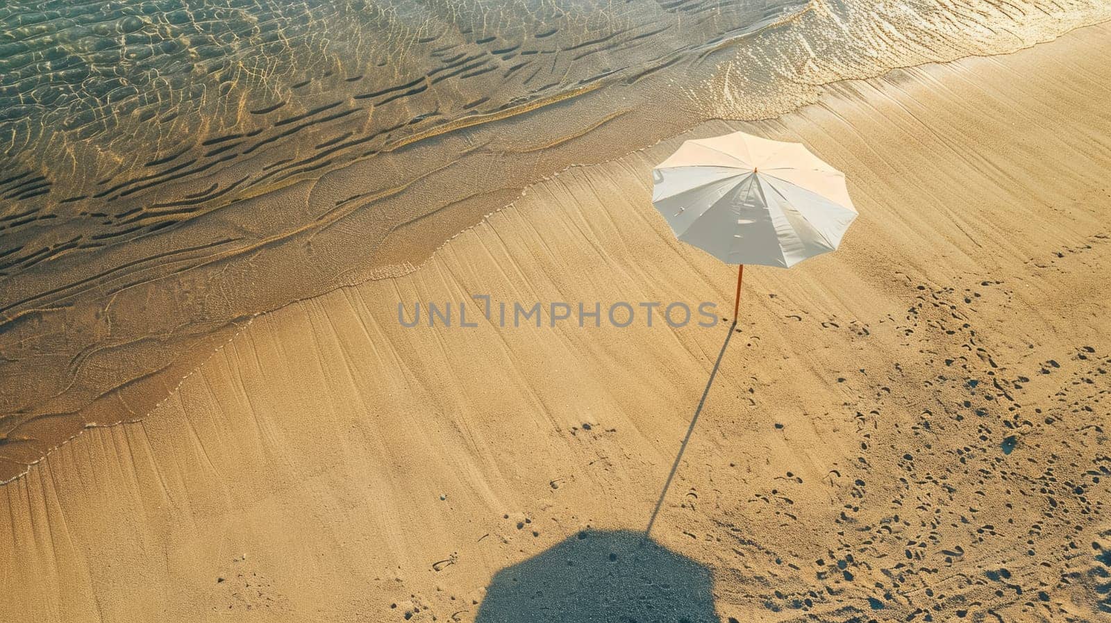 An umbrella rests on the sandy shore of the beach, overlooking the vast expanse of water. Travelers enjoy the scenic landscape as they relax on the shore AIG50