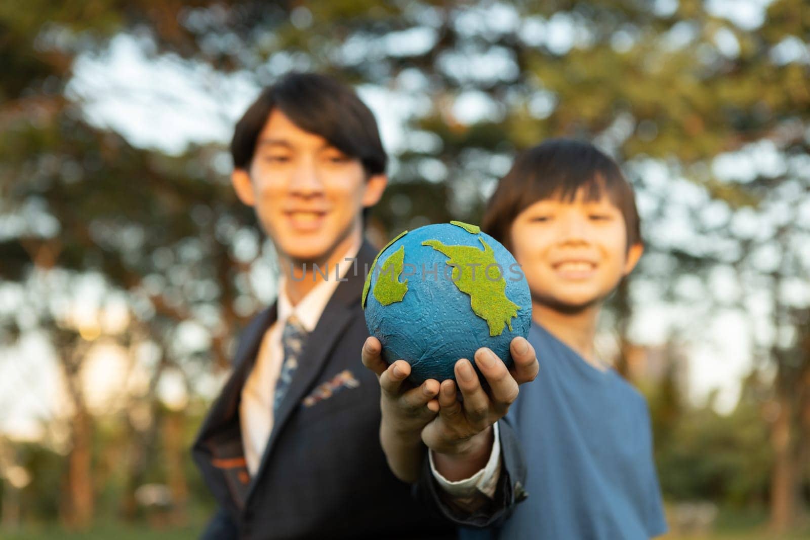 Focus Earth with blurred asian boy and businessman holding globe together. Gyre by biancoblue