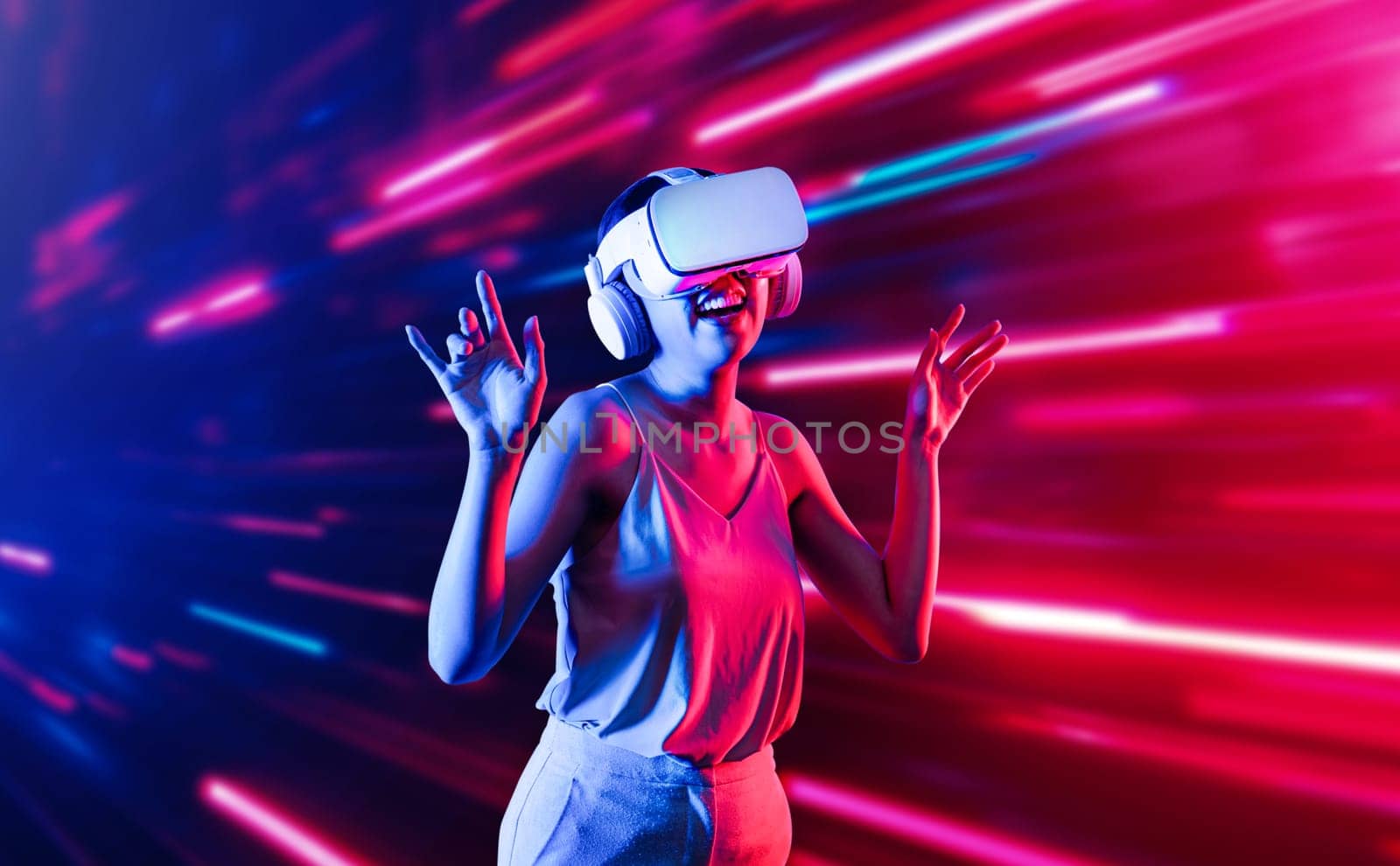 Smart female standing surrounded by neon light wearing VR headset connecting metaverse, future cyberspace community technology. Elegant woman enjoy dancing wavering body and sing song. Hallucination.