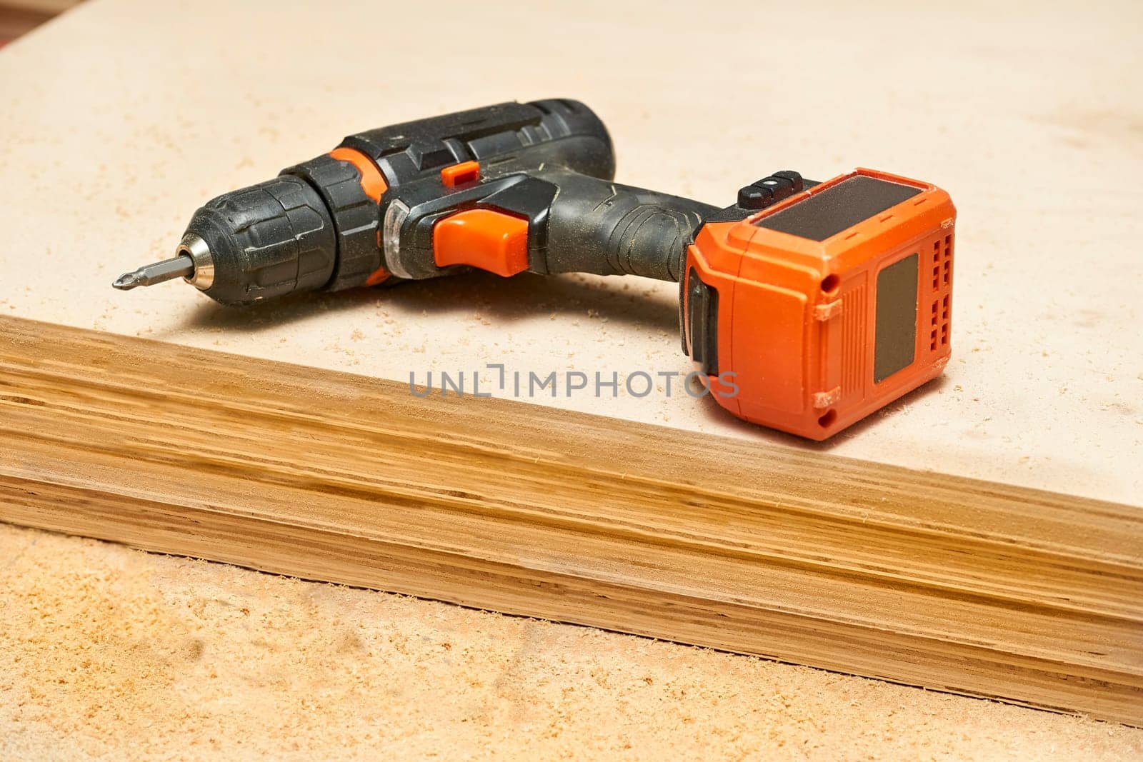 Electric drill,screwdriver on a plywood wooden surface with sawdust in workshop by jovani68