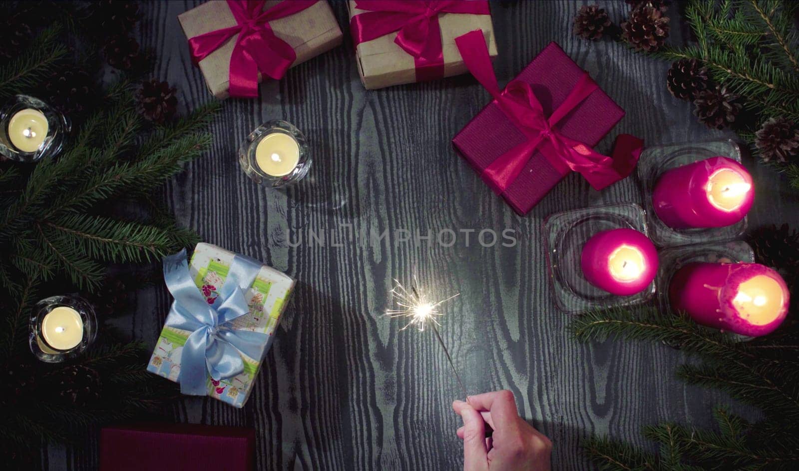 Top view female hand holding a sparkler. Table with Christmas decorations