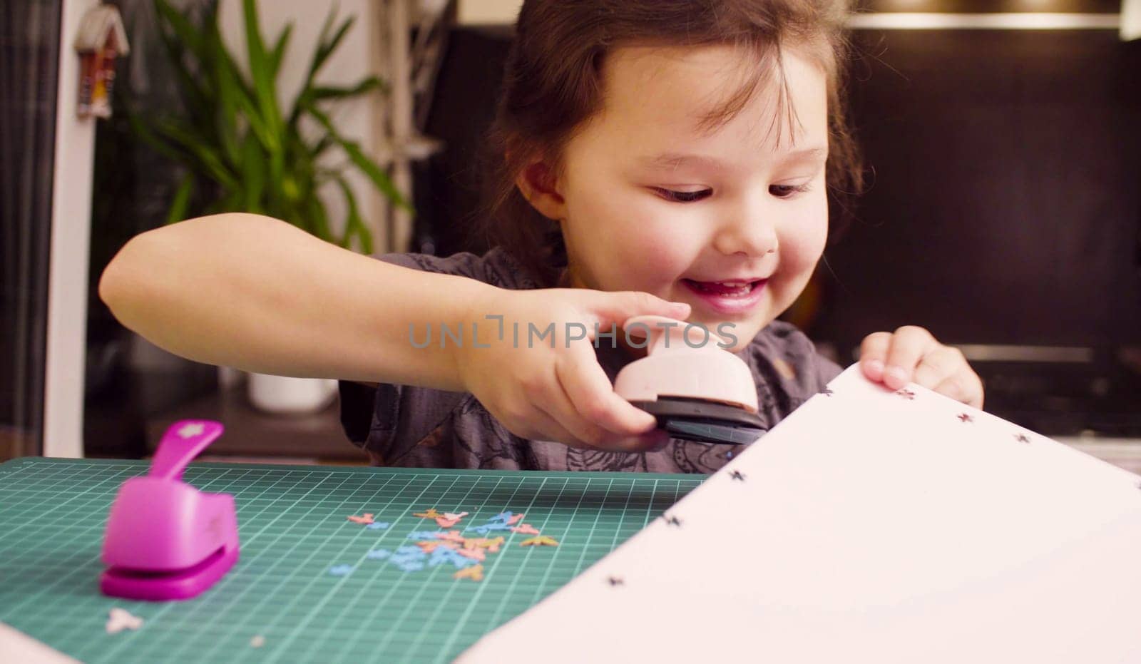 Little girl cutting flowers from white paper by Chudakov